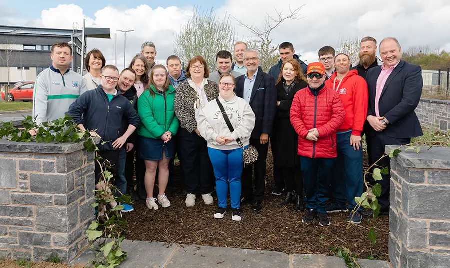 A group of people pose in the entrance of a new walled garden