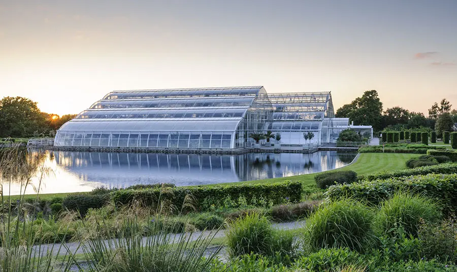 A large greenhouse surrounded by water and landscaped gardens