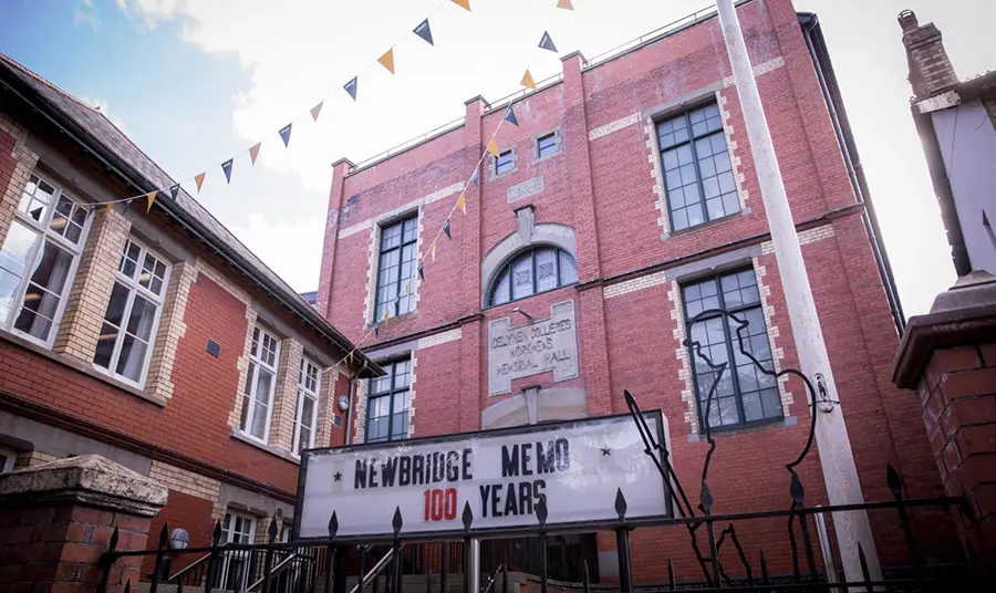 The exterior of a red brick building decorated with bunting and a sign that says "Newbridge Memo 100 years"
