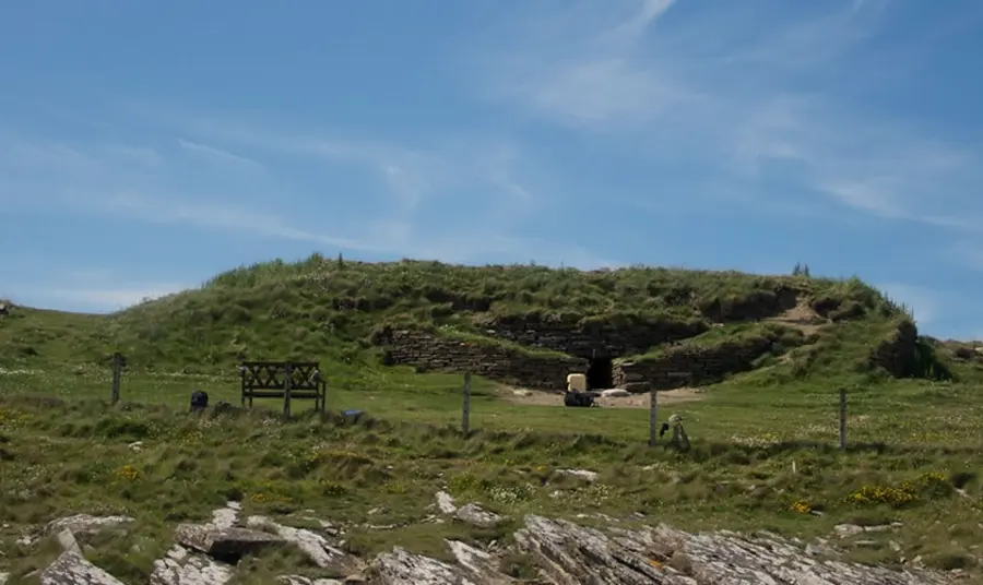 The tomb is a broad but flat earthwork with stonework around a low and narrow entrance.