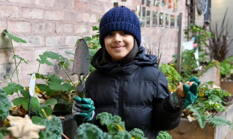 A girl holding a spade amongst plants