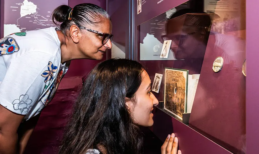 Two people bending down to look at a museum display about Duleep Singh