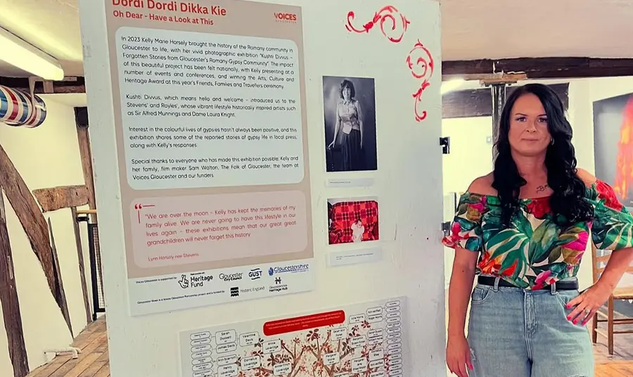 A community grant recipient stands next to an interpretation board with exhibition information