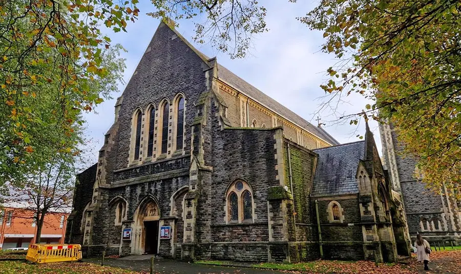The outside of a large stone church in autumn