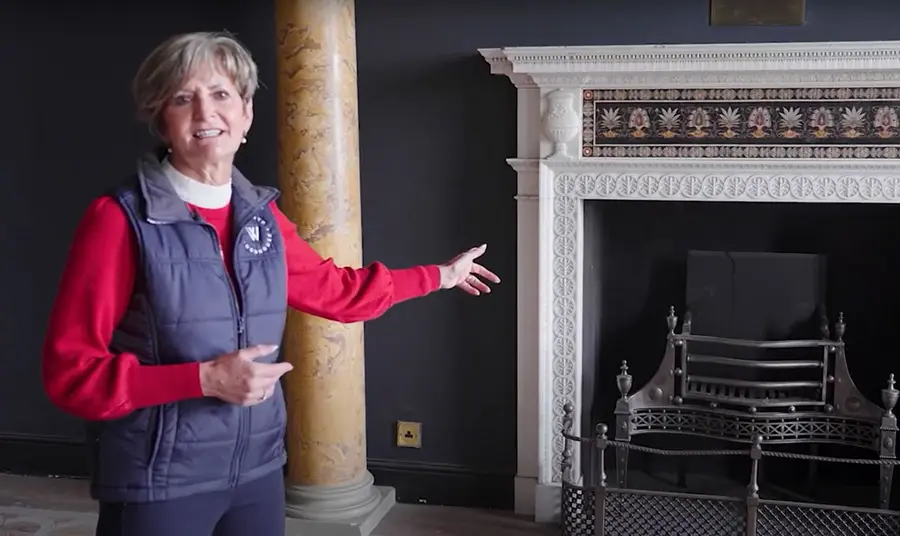 A woman standing in front of a large fireplace