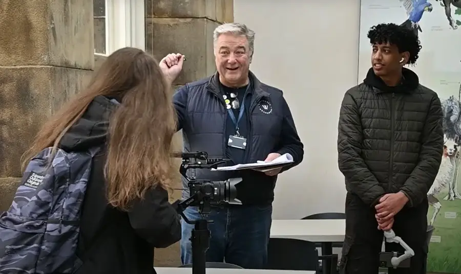 Three people working on a film shoot - one person operating a camera, another directing and a third looking on