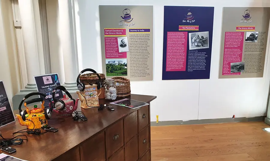 A table on the left featuring tea pots, and informational panels on the wall straight ahead