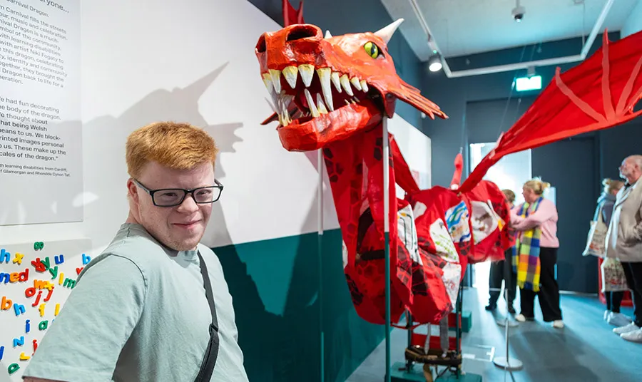 A person stands next to a large hand-made dragon sculpture