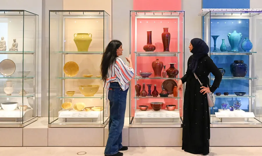 Two women looking at a museum display of ceramics