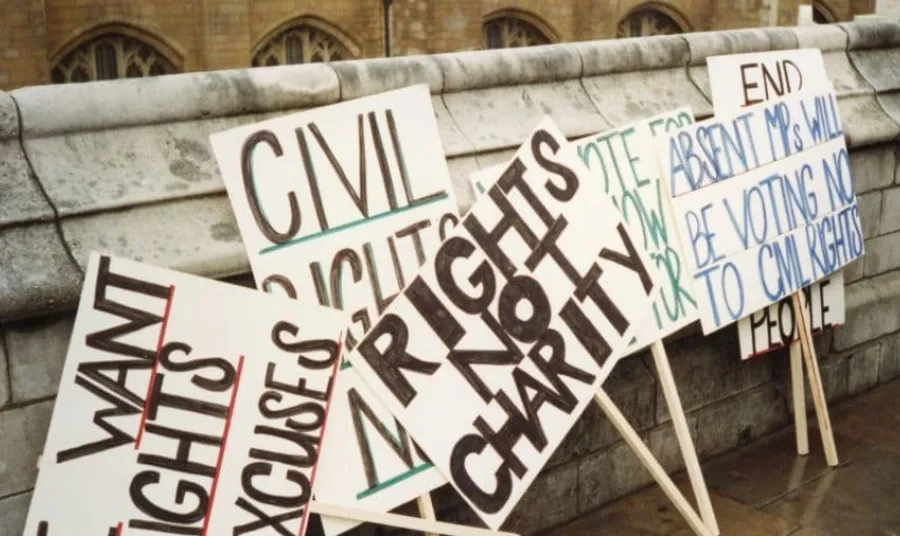 Placards for a demonstration about rights for disabled people, such as 'rights not charity'