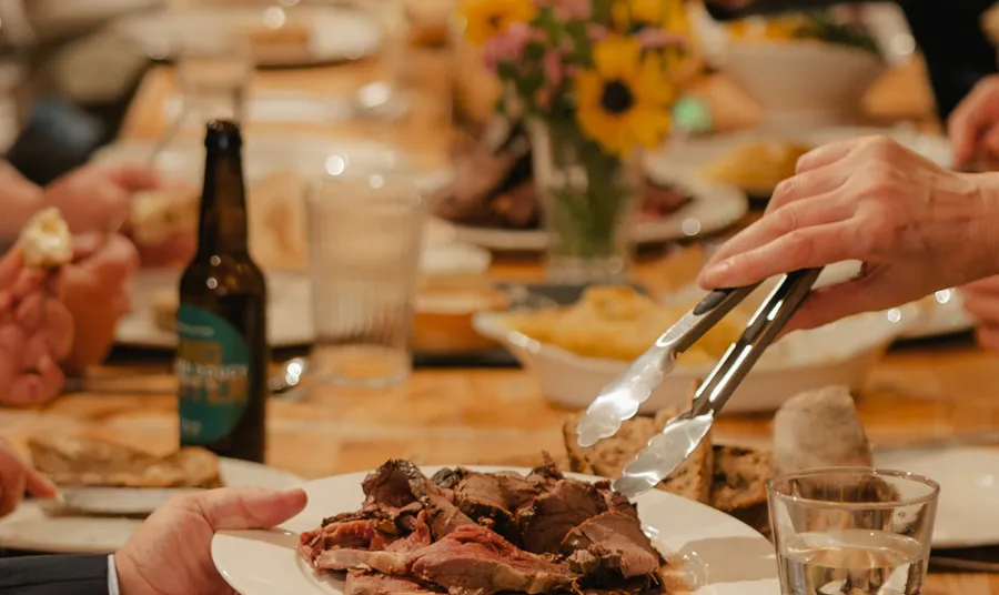 A close up of people sitting at a banquet table, helping themselves to food and drinks