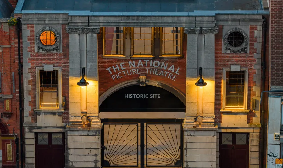 The brick and stone facade has been restored and is lit up at night