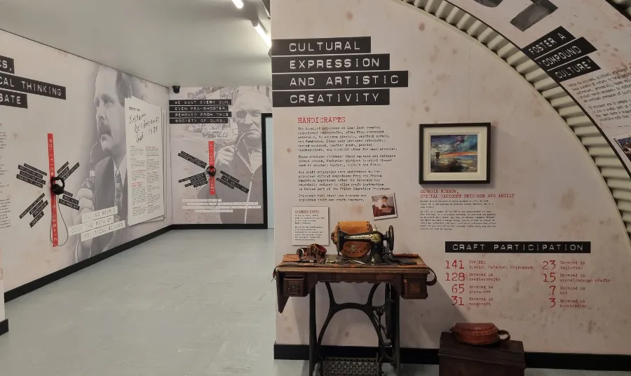 A exhibition space containing and sewing machine and text and images on white walls