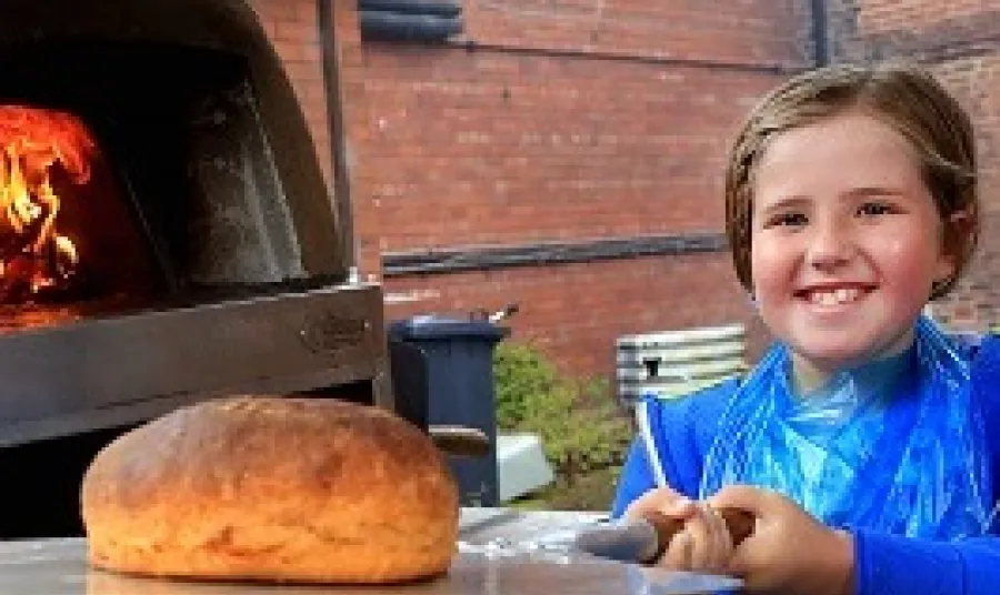 Young child making traditional bread in historic oven