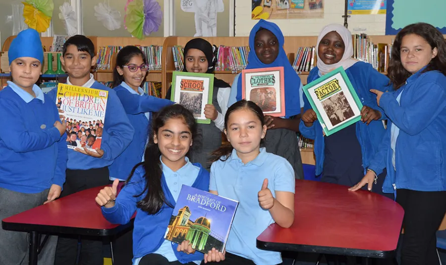 Group of children hold books whilst looking at the camera