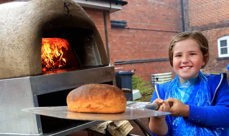 Girl puts loaf in oven