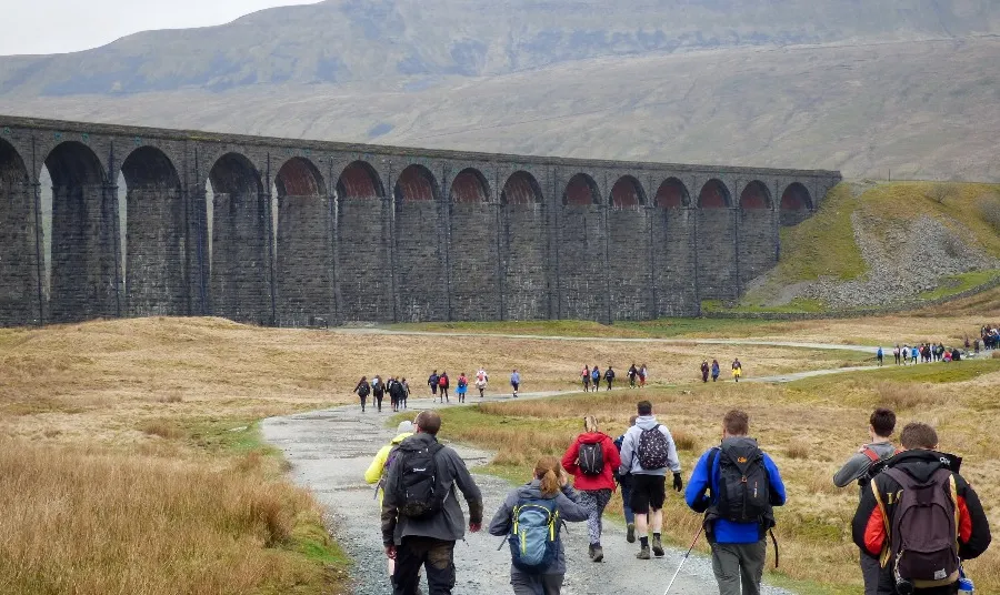 People walking along a country path by a viaduct in Yorkshire