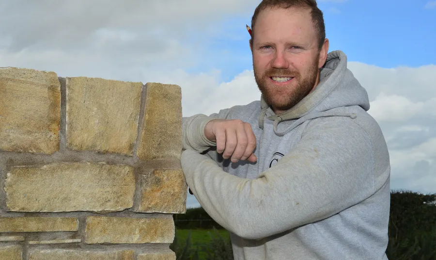 Conor Scullion posing next to some stonework