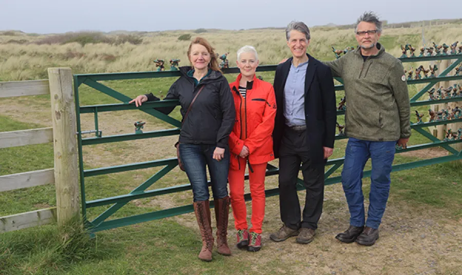 Four people stand in front of a fence