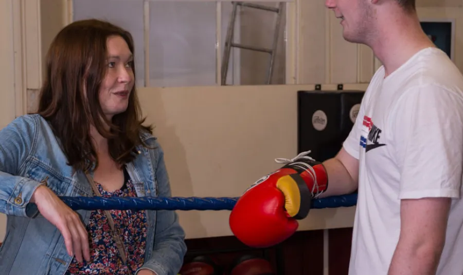 A woman talks to a young male boxer