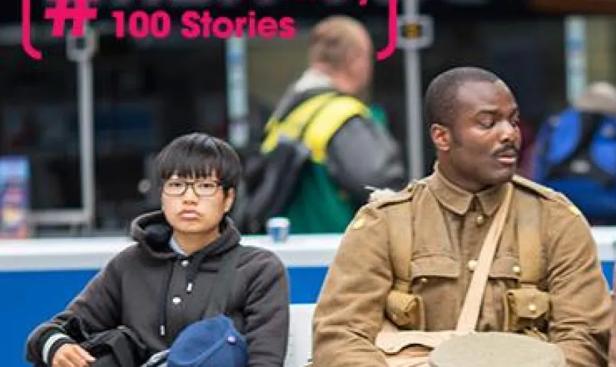 21st century man dressed as First World War soldier sitting next to commuters in a train station  