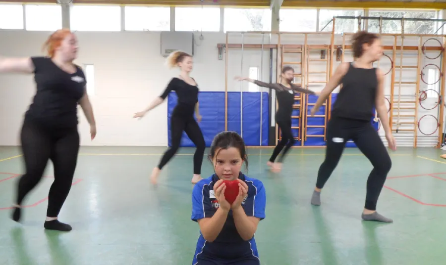 A young girl holds a heart surrounded by dancers