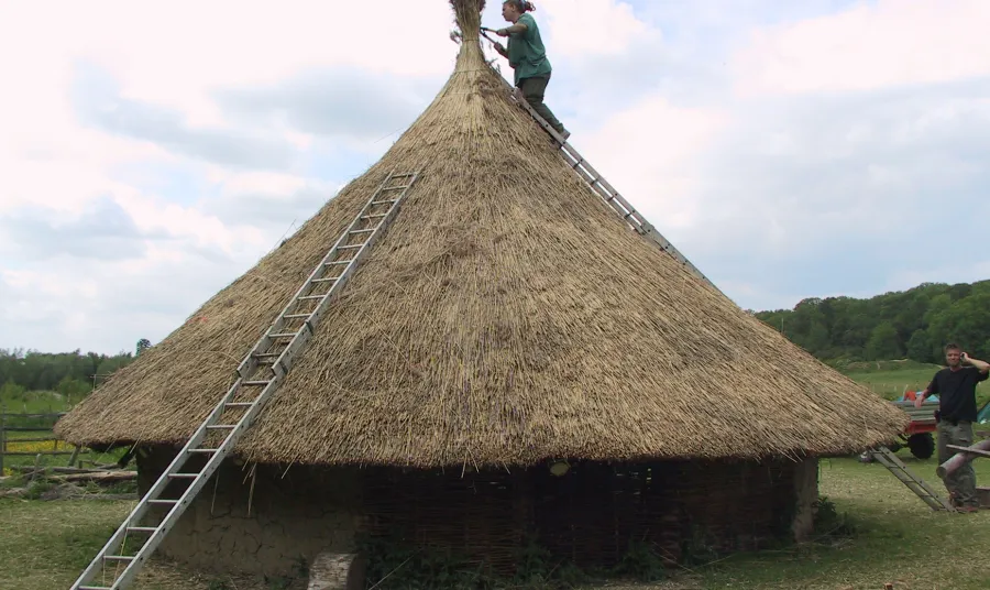 A trainee rethatches a roundhouse