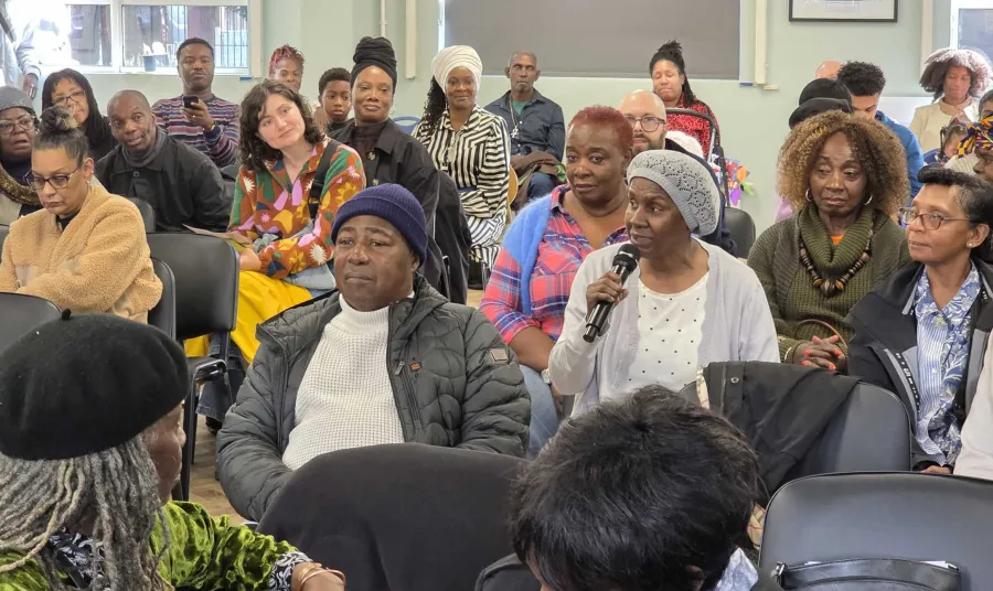 A seated audience turning to listen to an audience member holding a microphone