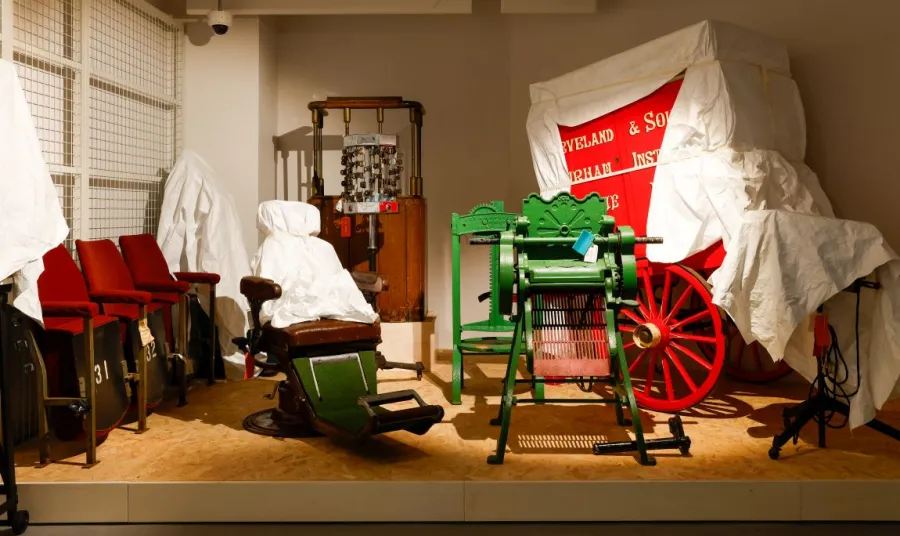 More objects, some under sheeting, in the Open Store, including a mangle, a barber's chair and a wooden wagon.