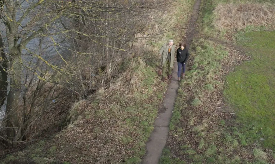 Andy Milne from The National Lottery Heritage Fund and Helen McCafferty from Green Action Trust walk along a riverside path.