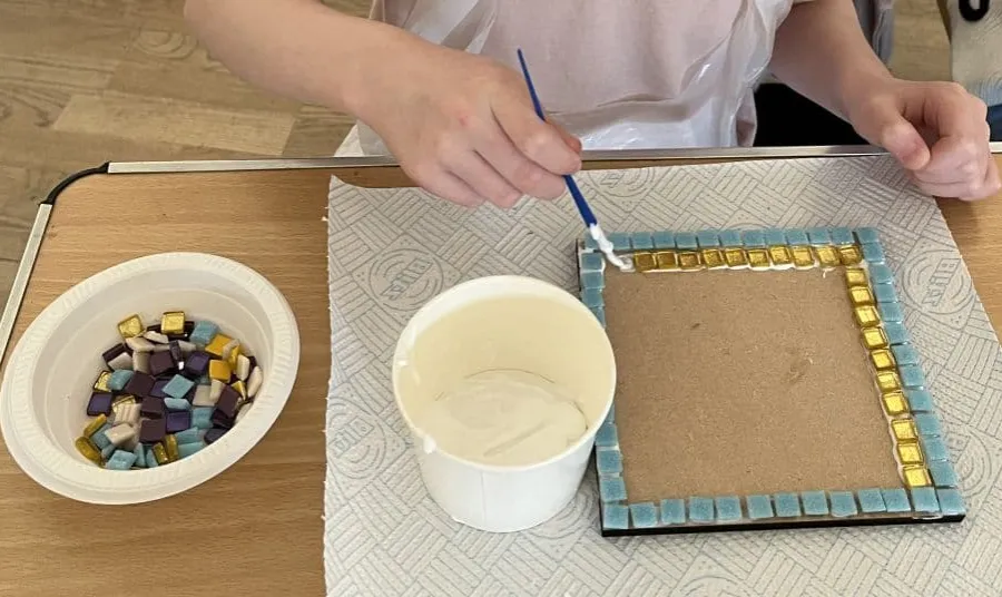 a person makes a mosaic using coloured tiles and glue