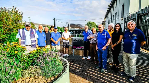 A group of adults pose for a photo at a station by a planter