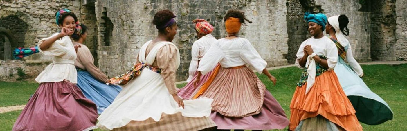 A group of women in period outfits dancing outside Porchester Castle