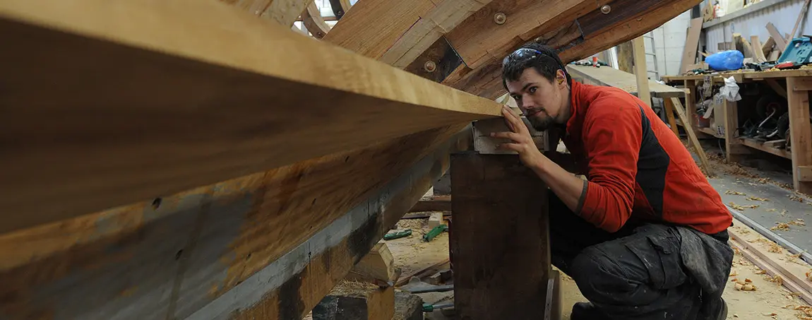 A person inspecting a wooden boat