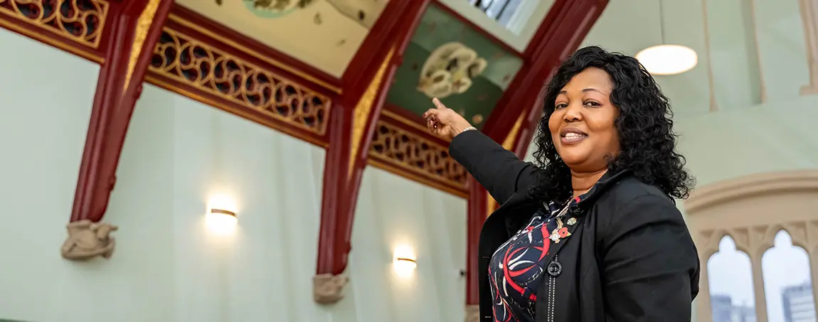 A person pointing at wall paintings on a curved ceiling