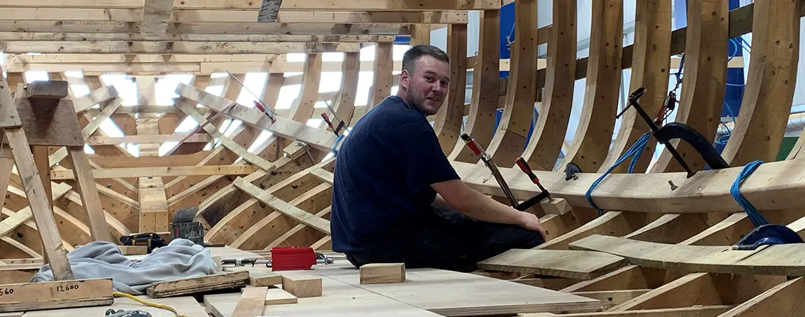 A person building the hull of a ship