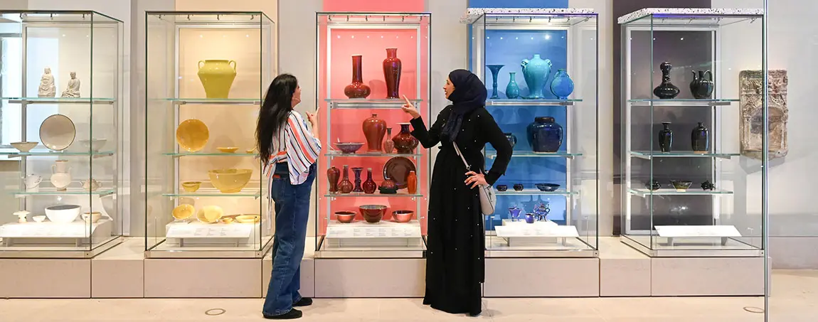 Two people looking at a museum display of ceramics