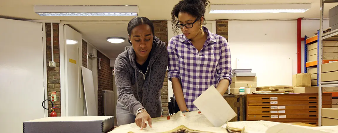 Two people look at an archive document