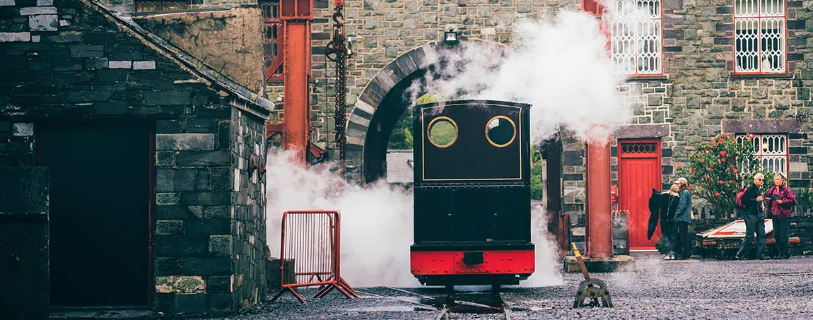 A small train billowing steam in a yard