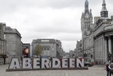 A view of Aberdeen City Centre. In the middle of the picture in large metal letters is a street art sculpture of the word Aberdeen.