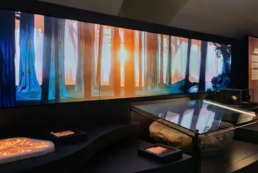 An exhibition features a display of the ancient stone in front picture of trees with the sun shining through