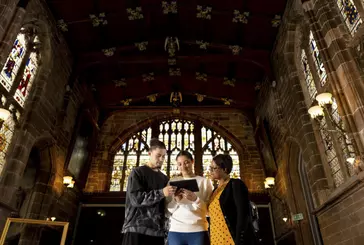 Three people use a digital device inside a historic place of worship