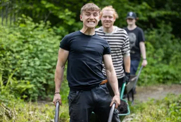 Person wheeling a wheelbarrow with a big smile