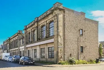 A row of cream coloured brick buildings with large windows.