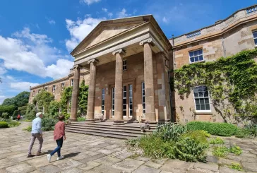 Two people walk towards a historic house