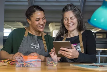 Two people using a computer tablet whilst smiling