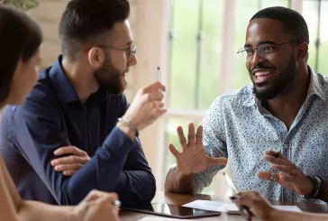 Three people sitting around a table discussing ideas