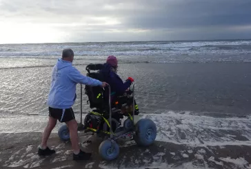 Person a scooter with big wheels by the sea with a companion