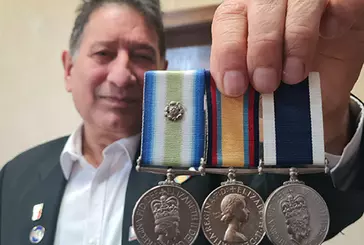 Person holds medals up to camera