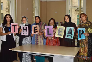 Group of people hold signs which spell out 'The Leap'